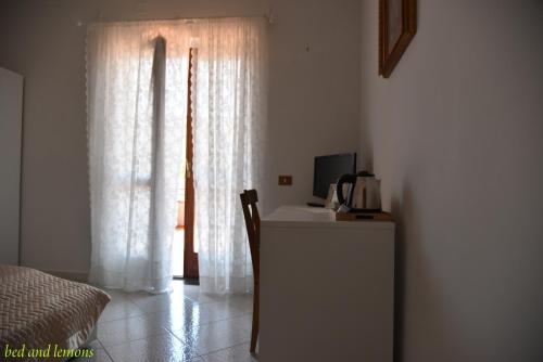 a bedroom with a desk and a bed and a window at Bed and Lemons in Piano di Sorrento