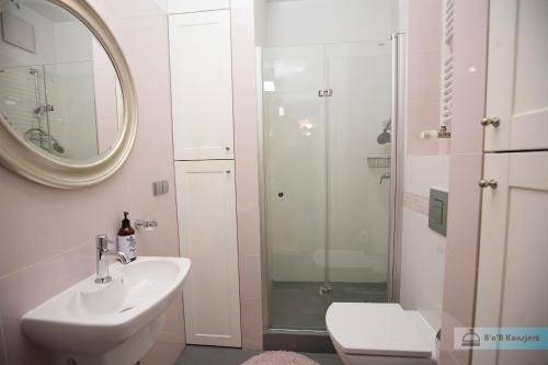 a white bathroom with a sink and a shower at Warsaw Concierge Vistula Apartment in Warsaw