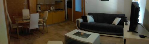 een woonkamer met een zwarte bank en een tafel bij Boro apartment in Kaštela