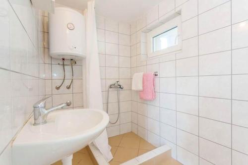 ein weißes Badezimmer mit Waschbecken und Fenster in der Unterkunft Apartment Sea Dream in Ston