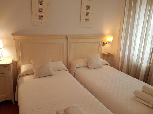 2 camas en una habitación de hotel con sábanas blancas en Tres Hermanos CON PISCINA PRIVADA, en Pelabravo