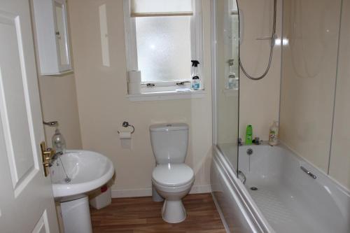 ein Badezimmer mit einem WC, einem Waschbecken und einer Badewanne in der Unterkunft Carrick Farm Lochside Appartment (GF) in Lochgoilhead