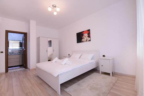 a white bedroom with a white bed and a window at Isaran 3P Apartment Brașov in Braşov