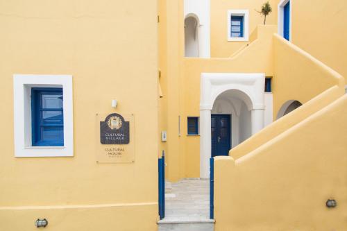 a yellow building with a blue door and stairs at Cultural House in Pirgos