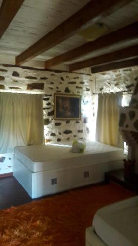 a bedroom with a white bed in a room with rocks at Vernon Villa Stone 1887 in Kastoria