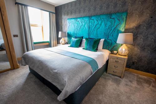 a bedroom with a large bed with a blue headboard at Heathmount Hotel in Inverness