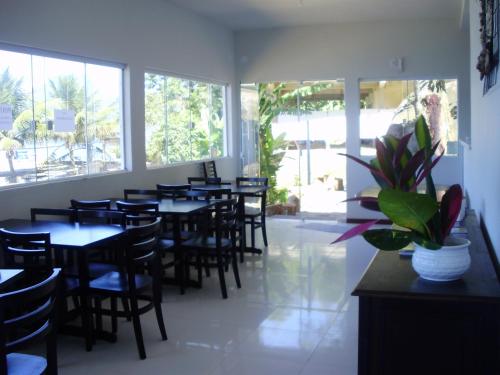 a dining room with tables and chairs and windows at Pousada Piquara in Mangaratiba