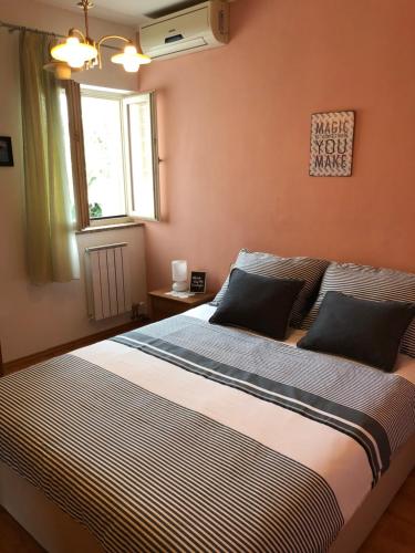 a bedroom with a large bed with striped sheets and a window at Apartment Danijela No. 2 in Novalja