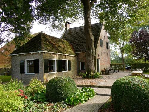 a stone house with a tree and a patio at de Boskpleats in Winsum