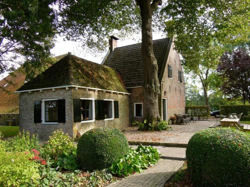 een stenen huis met een boom en een patio bij de Boskpleats in Winsum