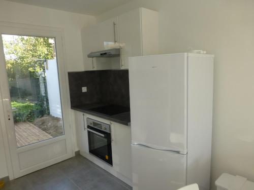 une cuisine blanche avec un réfrigérateur et une fenêtre dans l'établissement 5 Impasse Jean de la Fontaine, à Jard-sur-Mer