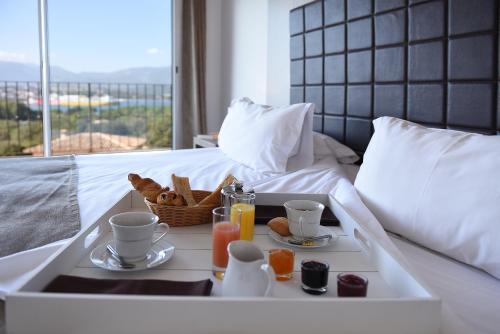 a tray with breakfast foods and drinks on a bed at Le San Lorenzo in Porto-Vecchio