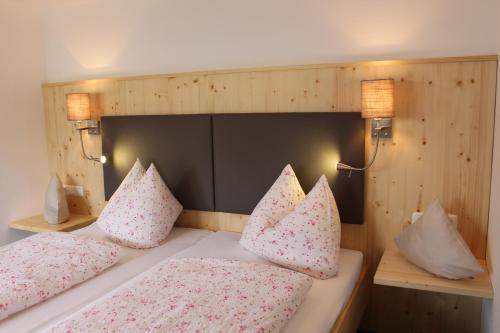 ein Schlafzimmer mit einem Bett mit rosa Kissen und zwei Lichtern in der Unterkunft Apart Wehrmeister in Jungholz