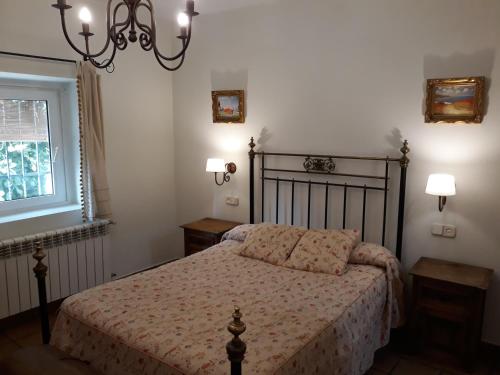 a bedroom with a bed and a window and a chandelier at La Casa de la Abuela in Casas del Monte