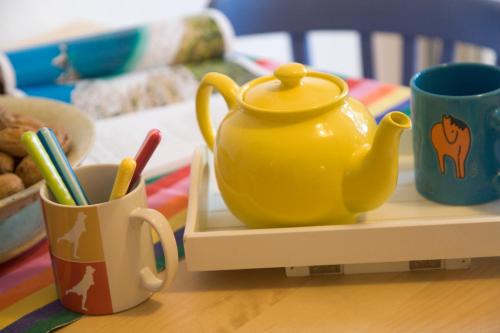 a yellow tea pot sitting on a table next to cups at Il Casale Di Montefreddo in Sirolo