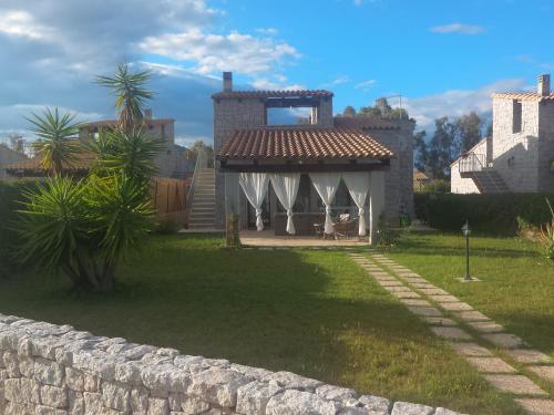 a house with a stone wall in a yard at Villa Cala Sinzias in Castiadas