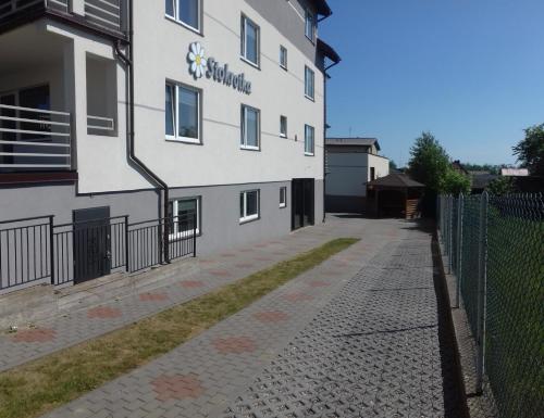 a white building with a fence next to a sidewalk at Stokrotka in Władysławowo