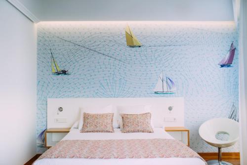 a bedroom with a bed and sailboats on the wall at Hotel Lino in Vigo