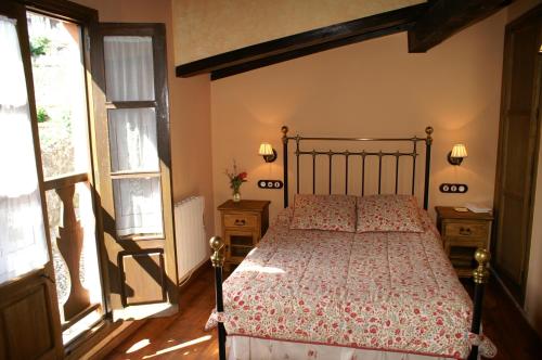 a bedroom with a bed and two windows at La Cuestecilla in Hervás