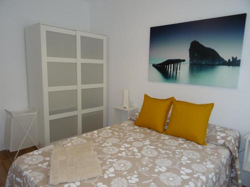 Un dormitorio con una cama con almohadas amarillas y una pintura en la pared. en Carmen Apartamentos, en Málaga