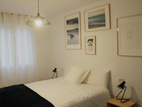 ブエウにあるApartamento Lapamánのベッドルーム1室(白いシーツと壁に絵画が飾られたベッド1台付)