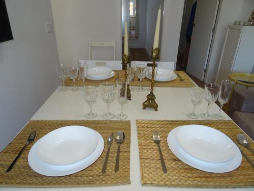a table with white plates and glasses and silverware at Carmen Apartamentos in Málaga