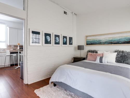 a white bedroom with a large bed and pictures on the wall at Downtown Memphis Shellcrest Apartments in Memphis