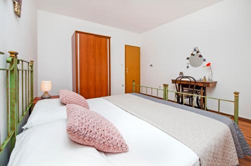 una camera da letto con un letto bianco e cuscini rosa di Apartman Lamanova a Rovigno (Rovinj)