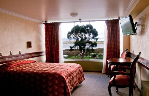 a hotel room with a bed and a table and a window at Taypikala Lago in Puno
