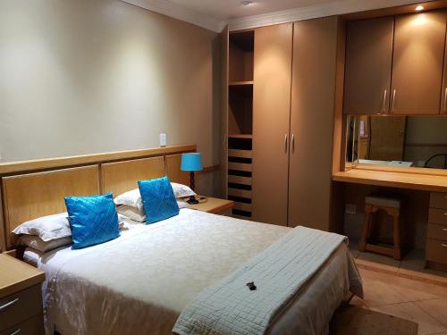 1 dormitorio con 1 cama grande con almohadas azules en Bubez Guesthouse en Barberton