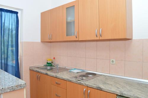 uma cozinha com armários de madeira e um lavatório em Apartmani Mačak II em Novalja