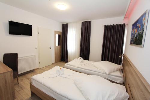 a hotel room with two beds and a television at Pension Villa Colosseo im Herzen von Meiningen in Meiningen