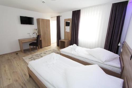 a hotel room with two beds and a desk at Pension Villa Colosseo im Herzen von Meiningen in Meiningen