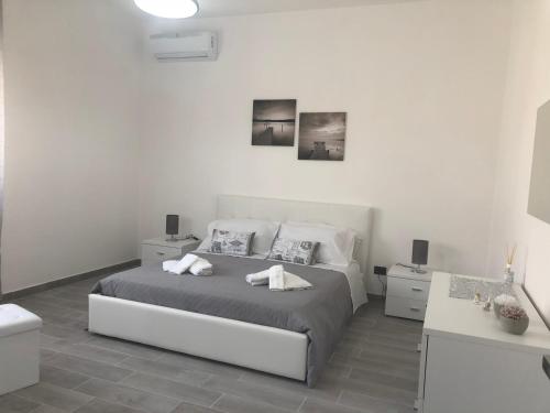 een witte slaapkamer met een bed en 2 handdoeken bij Solemar in Giardina Gallotti