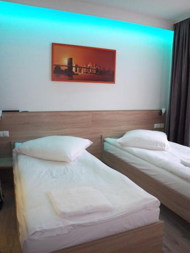 two beds in a hotel room with a blue light at Pension Villa Colosseo im Herzen von Meiningen in Meiningen