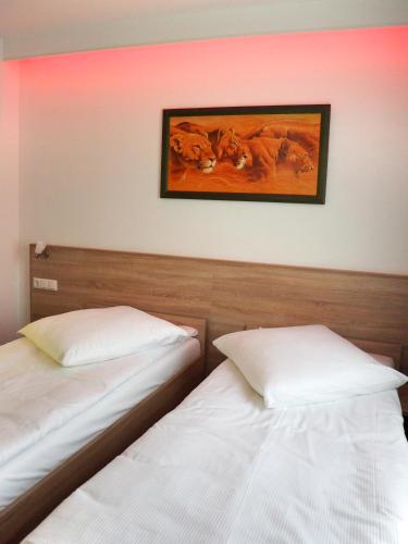 two beds in a room with a picture on the wall at Pension Villa Colosseo im Herzen von Meiningen in Meiningen