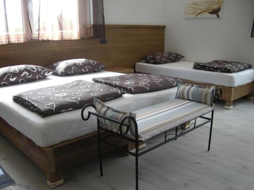 two twin beds in a room with a bench at B&B Il Crocevia in Teglio