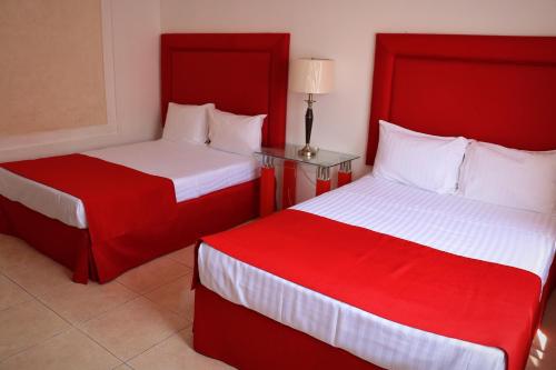 two beds in a hotel room with red and white sheets at Zar Guadalajara in Guadalajara