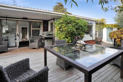 a patio with a table and chairs on a wooden deck at Relaxed 3BR Hideaway - Outdoor Living & Pets - Christchurch Holiday Homes in Christchurch