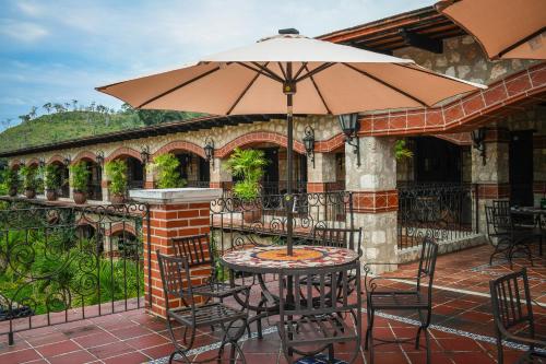 a table and chairs with an umbrella on a patio at Hacienda San Vicente in Flores