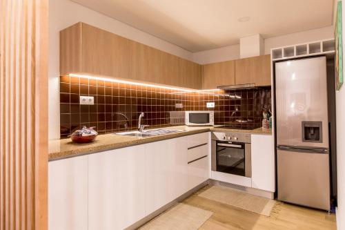 a kitchen with white cabinets and a stainless steel refrigerator at Casa do Tanque in Arouca