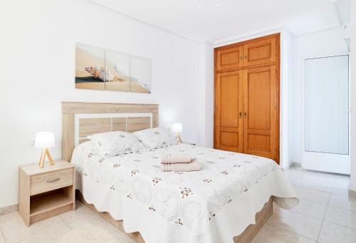 トレビエハにあるApartamento Rambla Juan Mateoの白いベッドルーム(ベッド1台、木製のドア付)