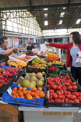 a woman standing in front of a fruit stand in a market at Serena Beach 2 in Nazaré