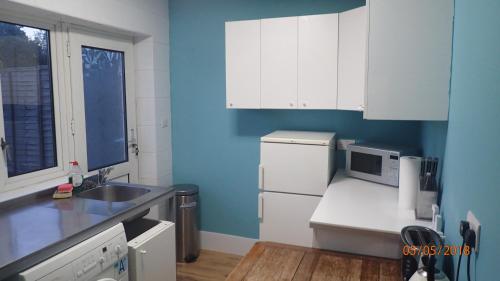 a kitchen with white cabinets and a blue wall at Hill Apartments in London