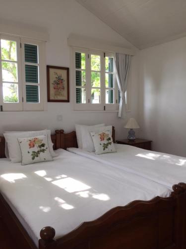 カロウラにあるMonserrate - Galera Cottageのベッドルーム1室(大きな白いベッド1台、窓2つ付)
