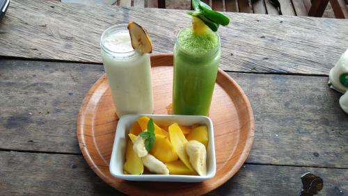 a plate with a drink and a bowl of fruit at The This-Kon Gili Meno in Gili Meno