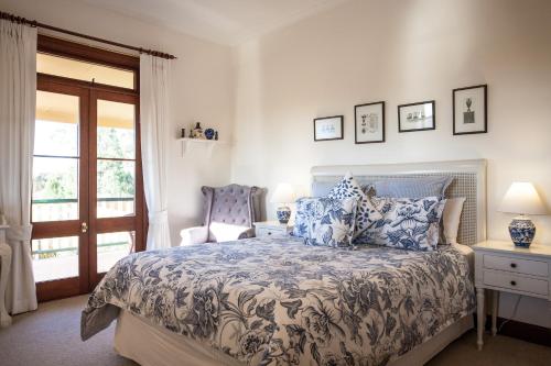 a bedroom with a bed and a chair and a window at Mudgee Homestead Guesthouse in Mudgee