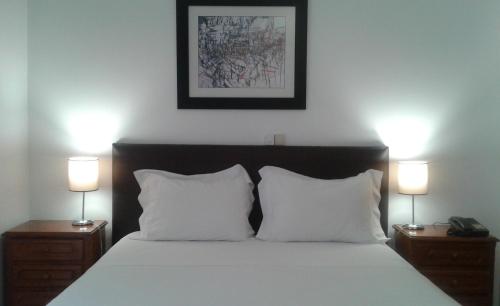 a bedroom with a bed with two lamps on night stands at Hotel Tic Tac in Bragança