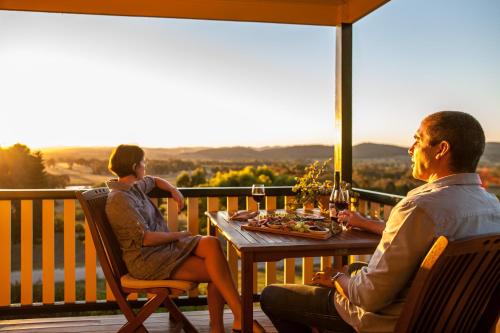 
a man and a woman sitting at a table with wine glasses at Mudgee Homestead Guesthouse in Mudgee
