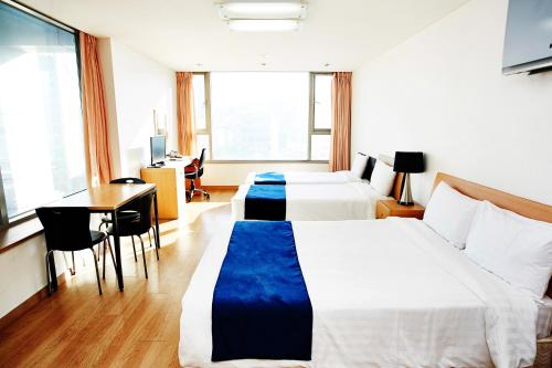 a hotel room with two beds and a desk at Hyundai Residence in Seoul